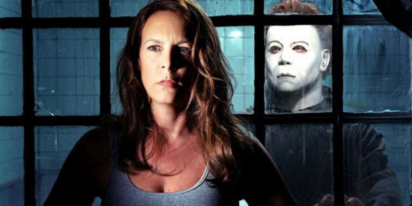 Laurie Strode standing in front of a window as a masked man looks through at her. 