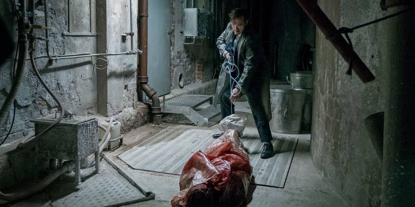 Jack drags a bloody body wrapped in plastic through a hallway in The House That Jack Built.