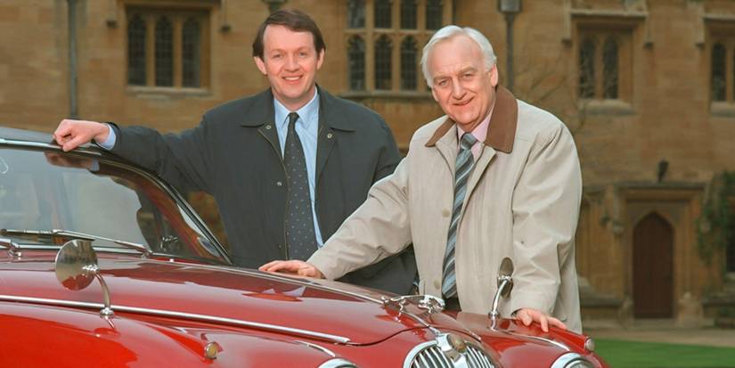 Inspector Morse stands in the yard of a large manner by his red car.