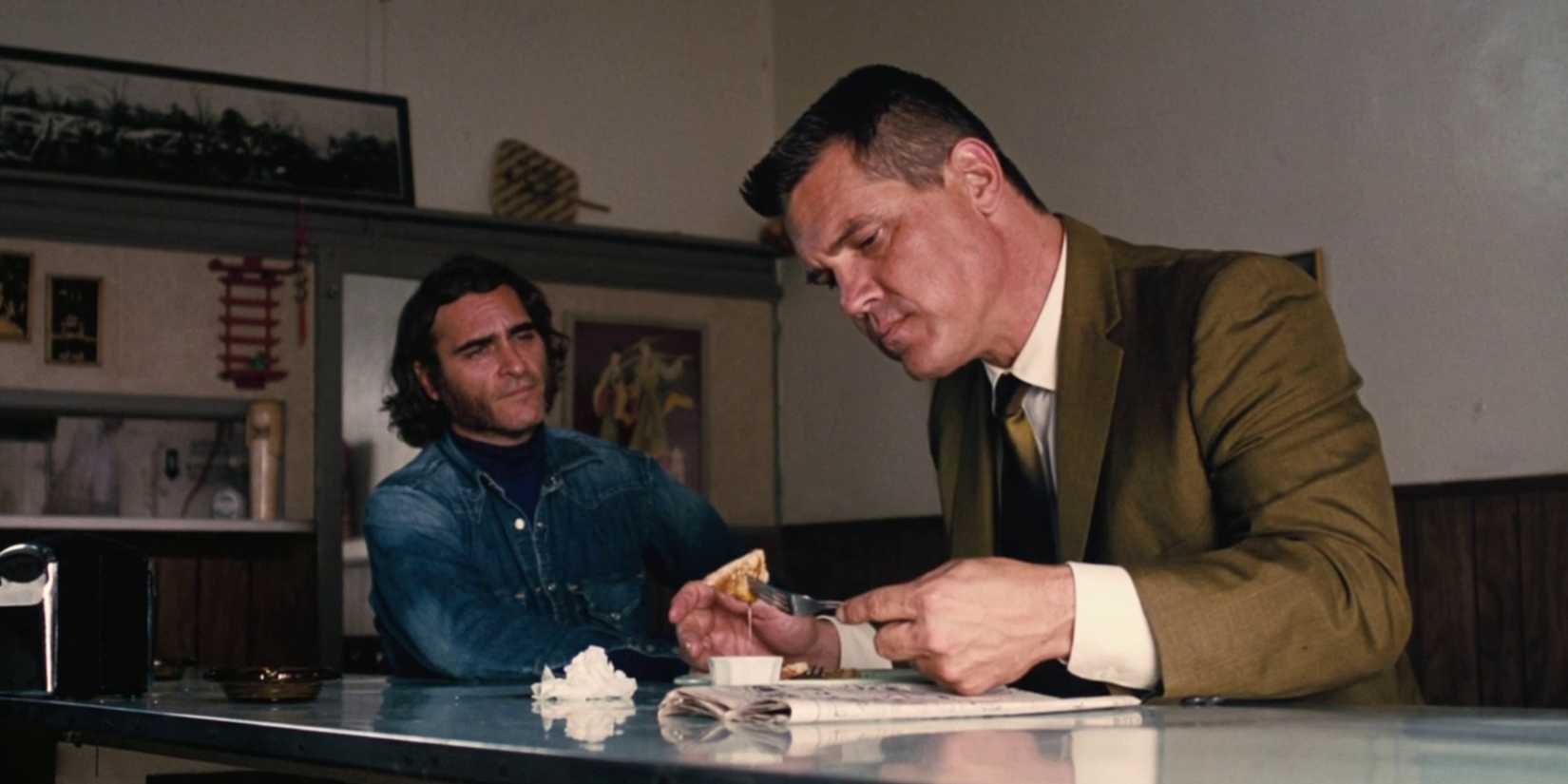 Joaquin Phoenix with Josh Brolin sitting at bench and eating in Inherent Vice