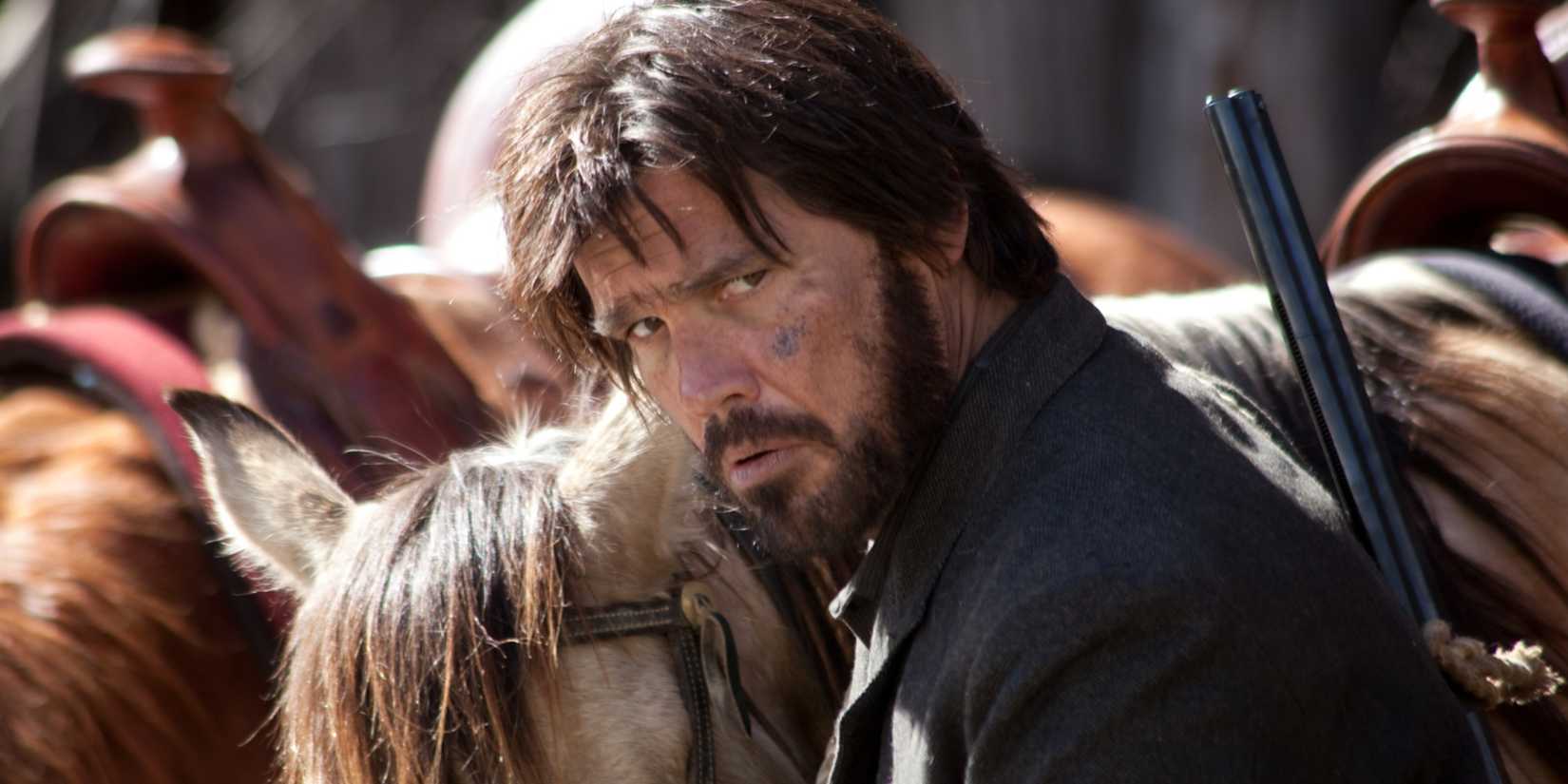 Josh Brolin looking up from attending to his horse in True Grit.