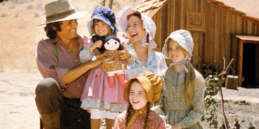 The Ingalls family laughs together in front of their home in Little House on the Prairie