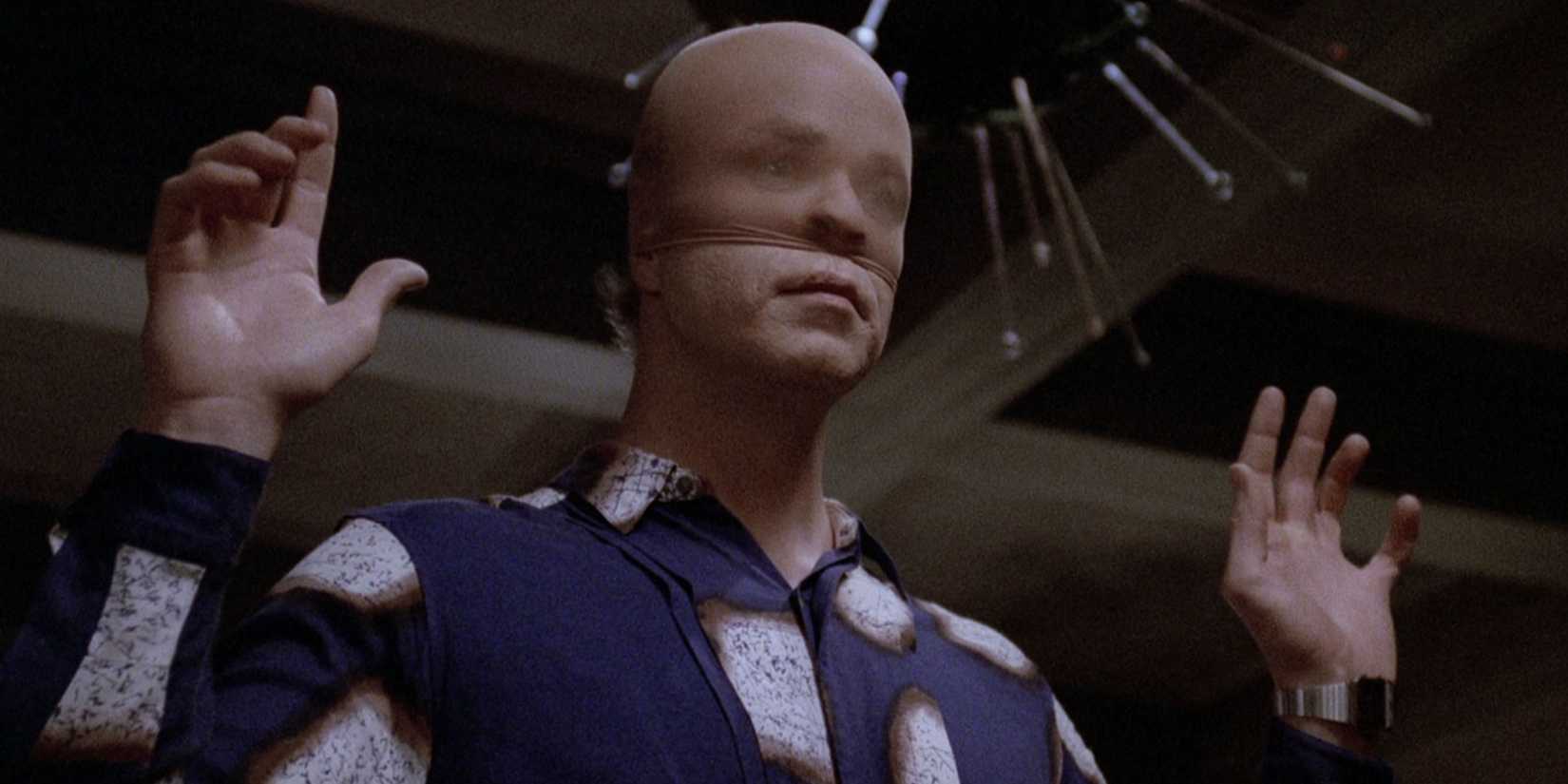 A man with a stocking on his face raising his hands in Manhunter