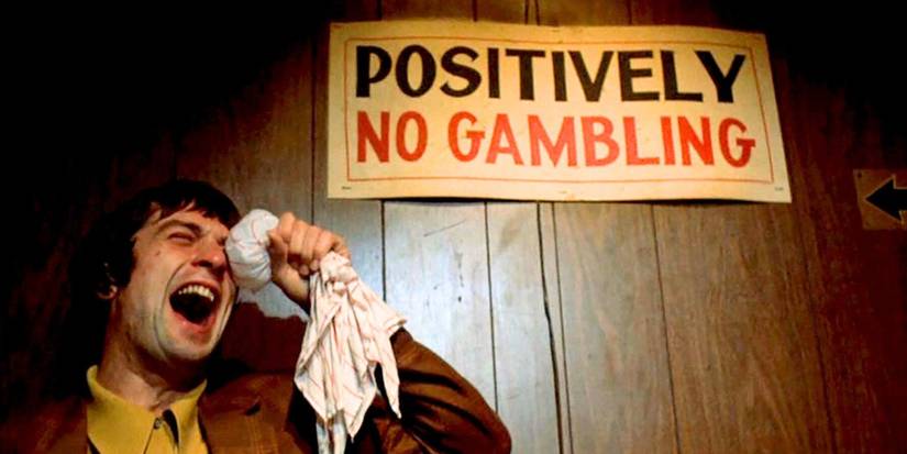Robert De Niro holding a cloth of ice to his eyes in front of a "positively no gambling" sign in Mean Streets