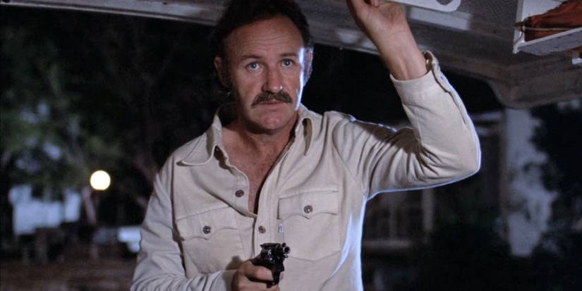 Harry Moseby (Gene Hackman) stands in the night aiming a revolver in 'Night Moves' (1975).