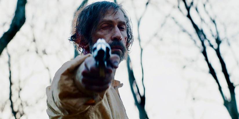 Tim Blake Nelson pointing a gun directly at the camera in 'Old Henry'
