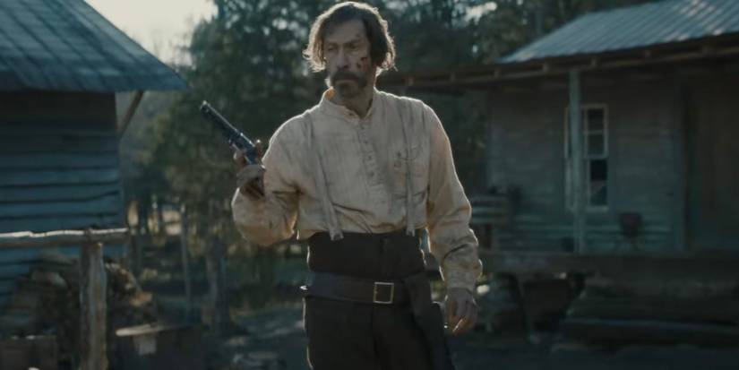 Tim Blake Nelson holding up a revolver in Old Henry