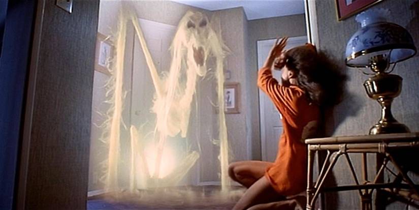 Penampakan kerangka di depan pintu dengan seseorang tampak ketakutan di depannya dalam Poltergeist, 1982.