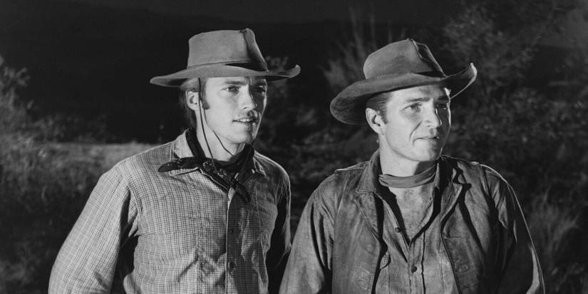 Rowdy Yates (Clint Eastwood) and Gil Favor (Eric Fleming) in cowboy hats looking at something off-screen on 'Rawhide'