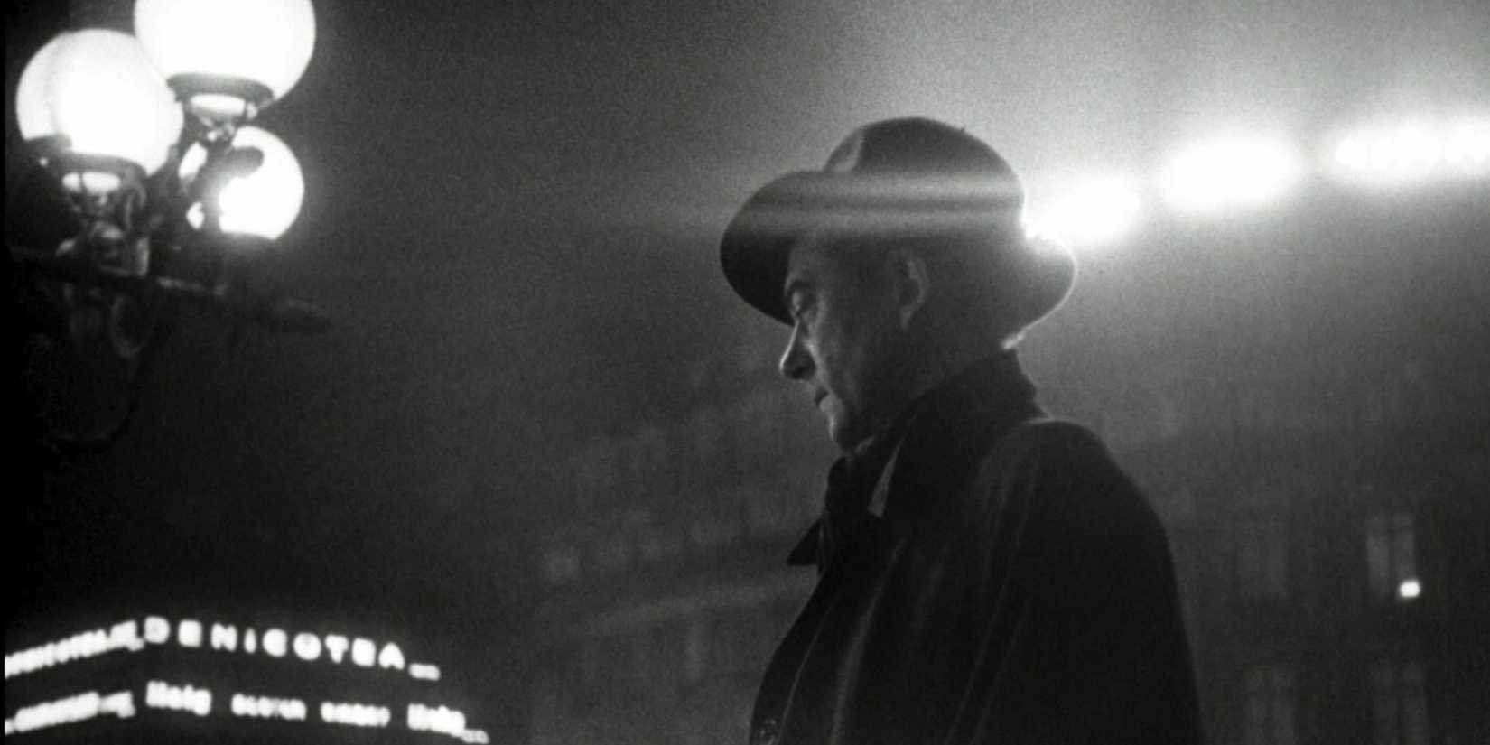A man standing in a lit city in Rififi