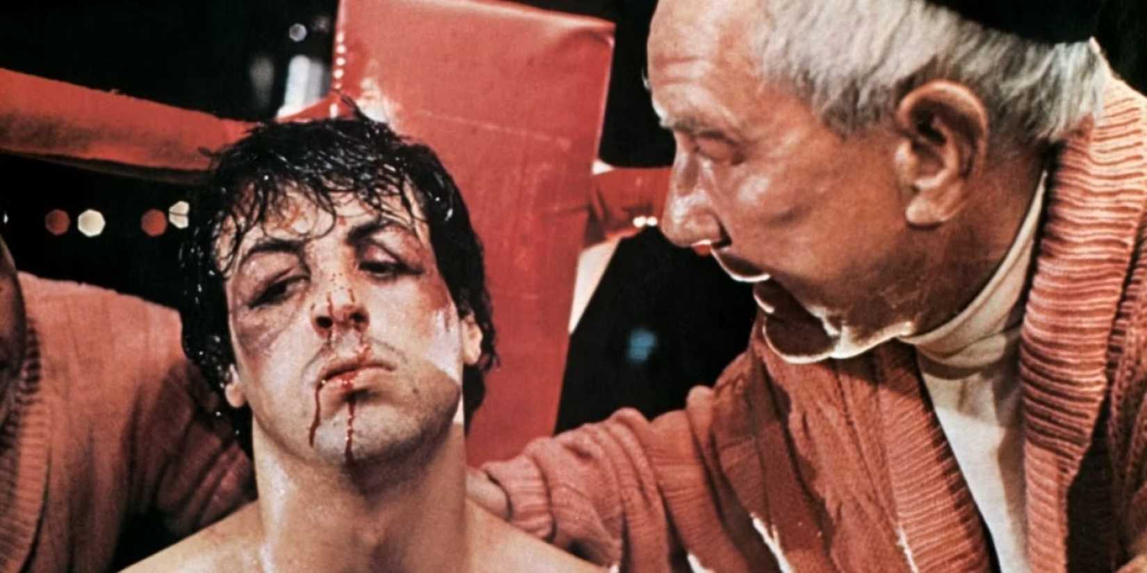 A bloodied and bruised Rocky (Sly Stallone) being talked to by Mickey (Burgess Meredith) in Rocky