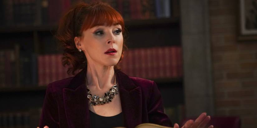Rowena MacLeod (Ruth Connell) reads a spell from a book as she sits in the Winchesters' bunker in 'Supernatural'