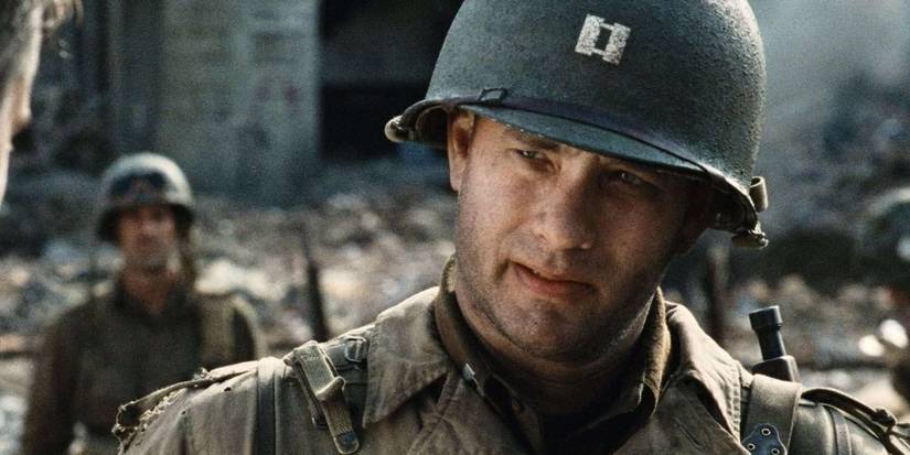 Tom Hanks as Captain John Miller in a ruined town wearing his army helmet in Saving Private Ryan.