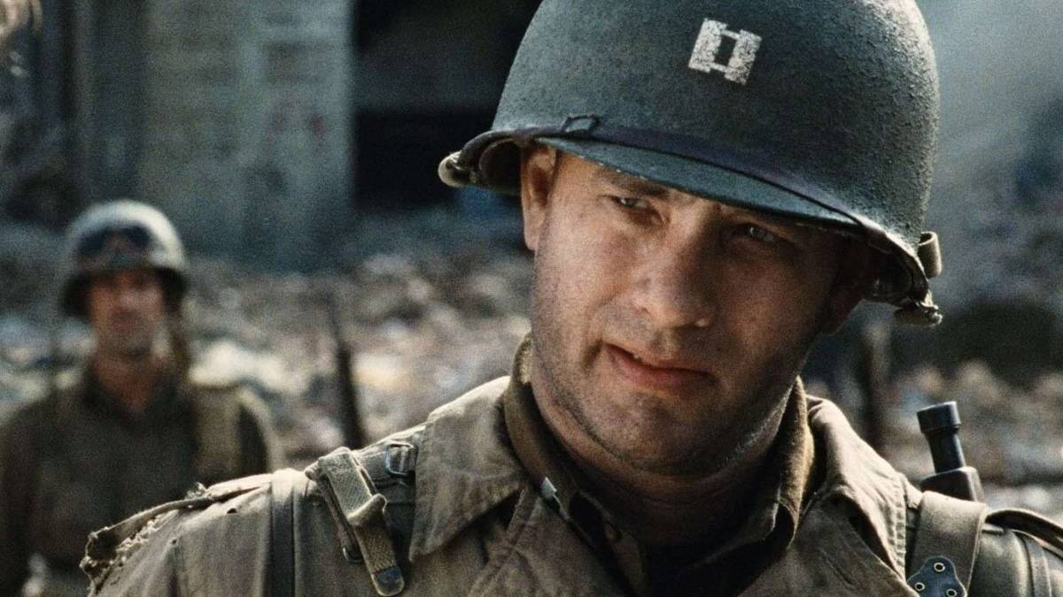 Tom Hanks as Captain John Miller in a ruined town wearing his army helmet in Saving Private Ryan.