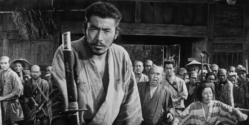 A samurai looking intently ahead with a group of people standing behind him in Seven Samurai.