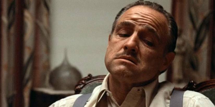 Marlon Brando as Vito Corleone, sitting and looking down in The Godfather