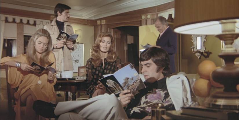 A group of wealthy visitors to a yacht party lounge around in a living area in 'The Last of Sheila' (1973)