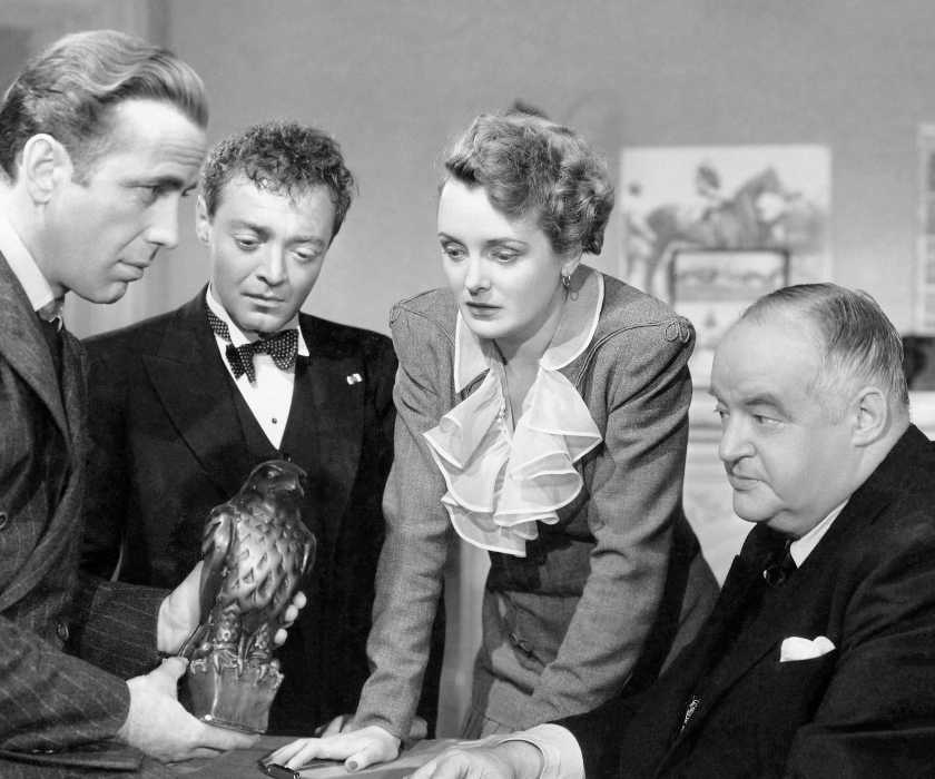 Brigid O'Shaughnessy, Sam Spade, and others huddle around the Falcon statue in The Maltese Falcon