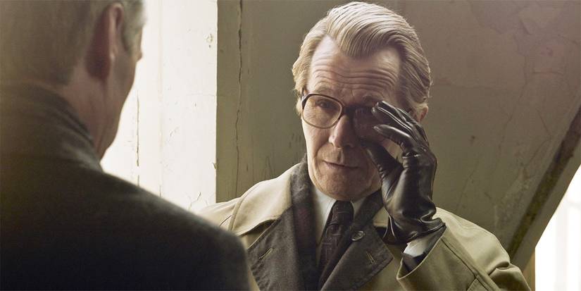 Gary Oldman as George Smiley with a gloved hand adjusts his glasses in Tinker Tailor Soldier Spy