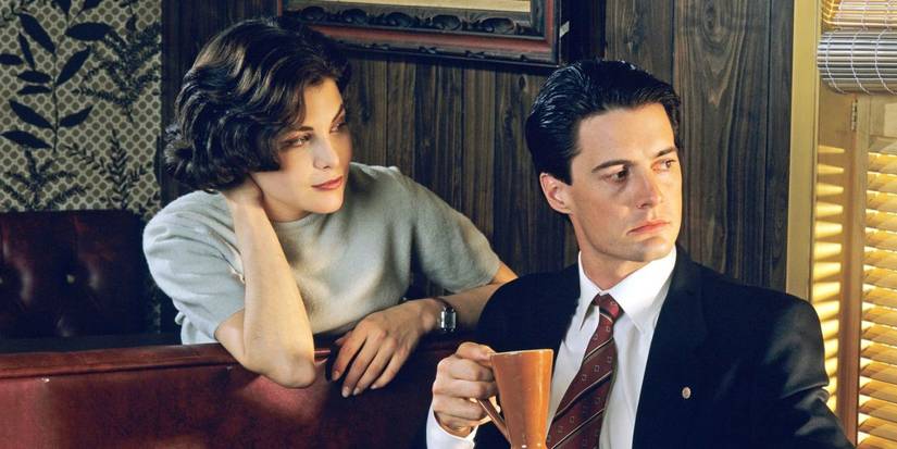 Audrey Horne (Sherilyn Fenn) looks at Dale Cooper (Kyle MacLachlan) as he looks out a window in Twin Peaks.