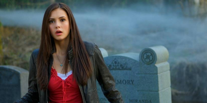 Nina Dobrev as Elena Gilbert, standing in a cemetery looking shocked in Season 1 of The Vampire Diaries.
