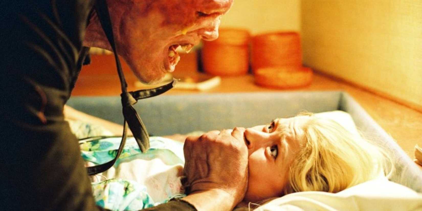 A creature covering a scared woman's mouth in The Hills Have Eyes (2006)