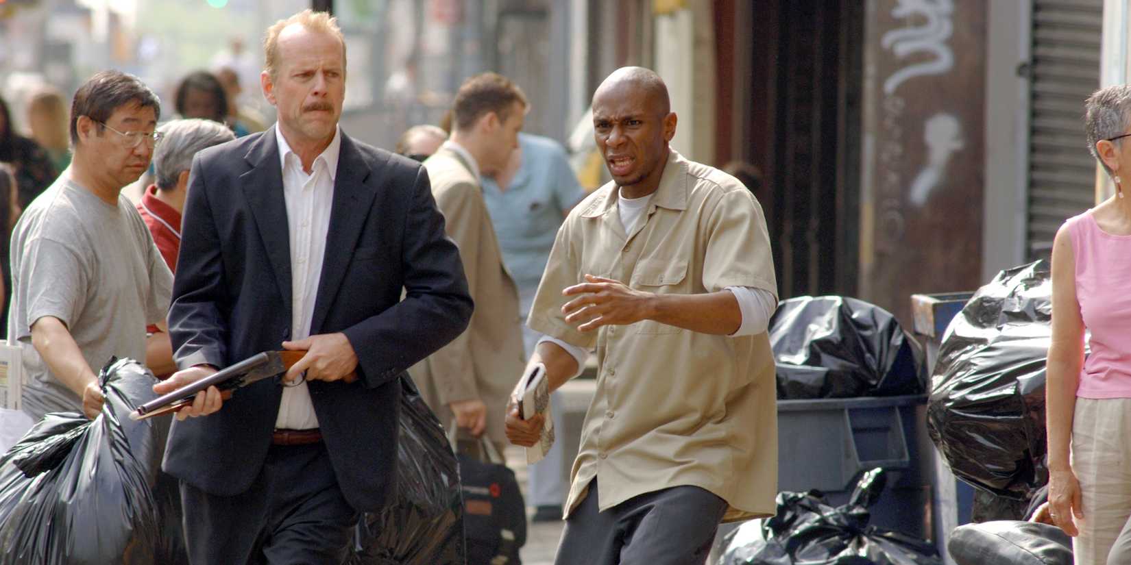 Bruce Willis holding a rifle and walking down the street in 16 Blocks