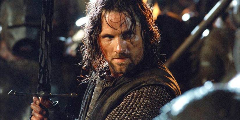 Aragorn, played by actor Viggo Mortensen, stands with his sword raised, covered in orc blood in The Lord of the Rings: The Fellowship of the Ring.