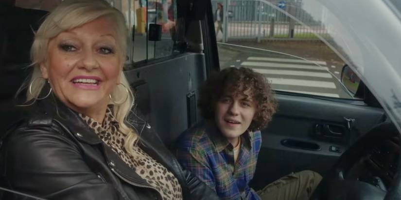 Dylan Llewellyn and Camille Coduri look out the window as they sit in a car and smile in Big Boys.