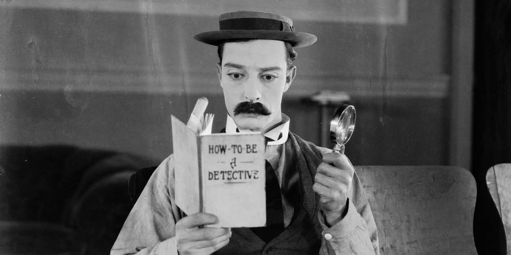Buster Keaton reads How to Be a Detective while donning a magnifying glass and fake mustache in 'Sherlock Jr.'