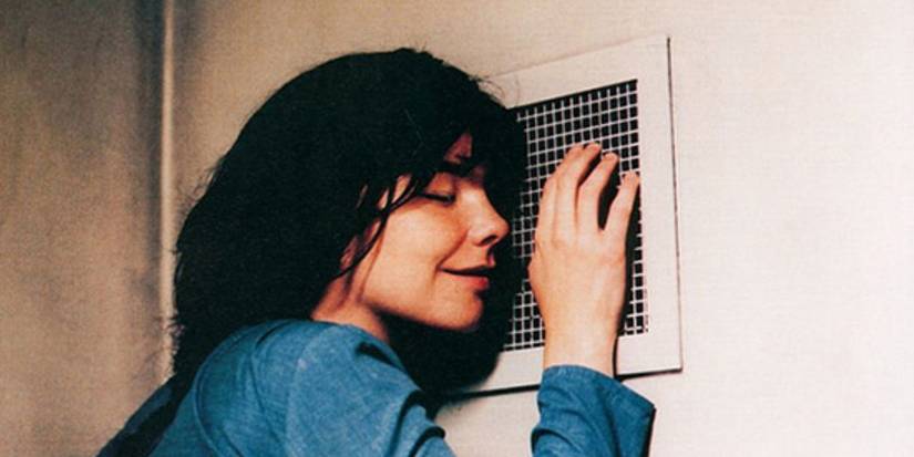 Selma (Bjork) smiles while leaning against a ventilation cover on the wall