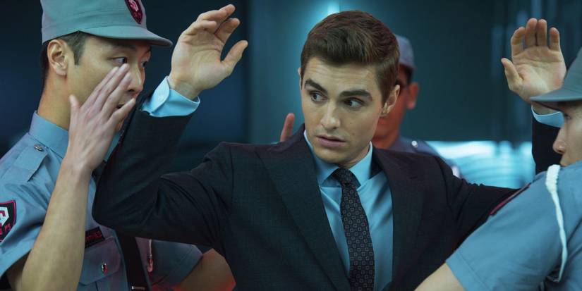 Dave Franco as Jack Wilder looks annoyed with arms in the air being frisked by security in Now You See Me 2.