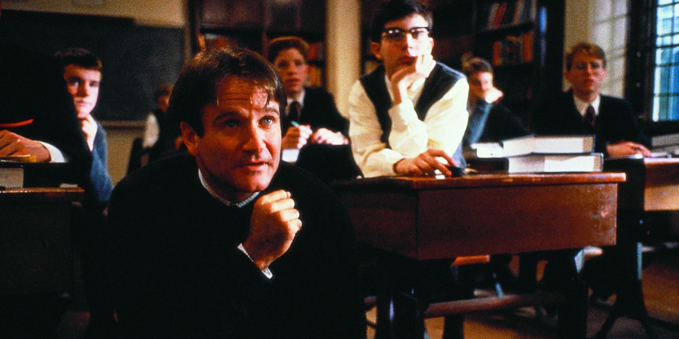 Robin Williams with an awed expression listening to a student who is off-screen in Dead Poets Society.