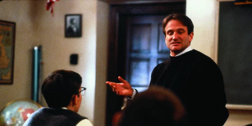 John Keating speaks at the front of the classroom with his right hand raised in Dead Poets Society