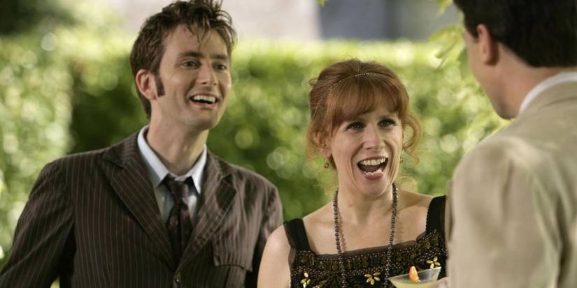 The Doctor and Donna Noble smiling widely as they greet someone who's standing offscreen to the right in Doctor Who