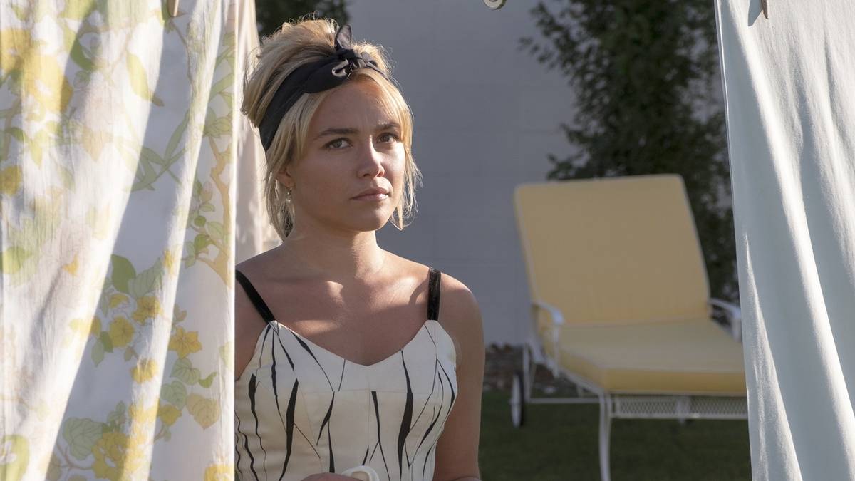Florence Pugh as Alice Chambers, standing outside among hanging sheets and looking concerned in Don't Worry Darling