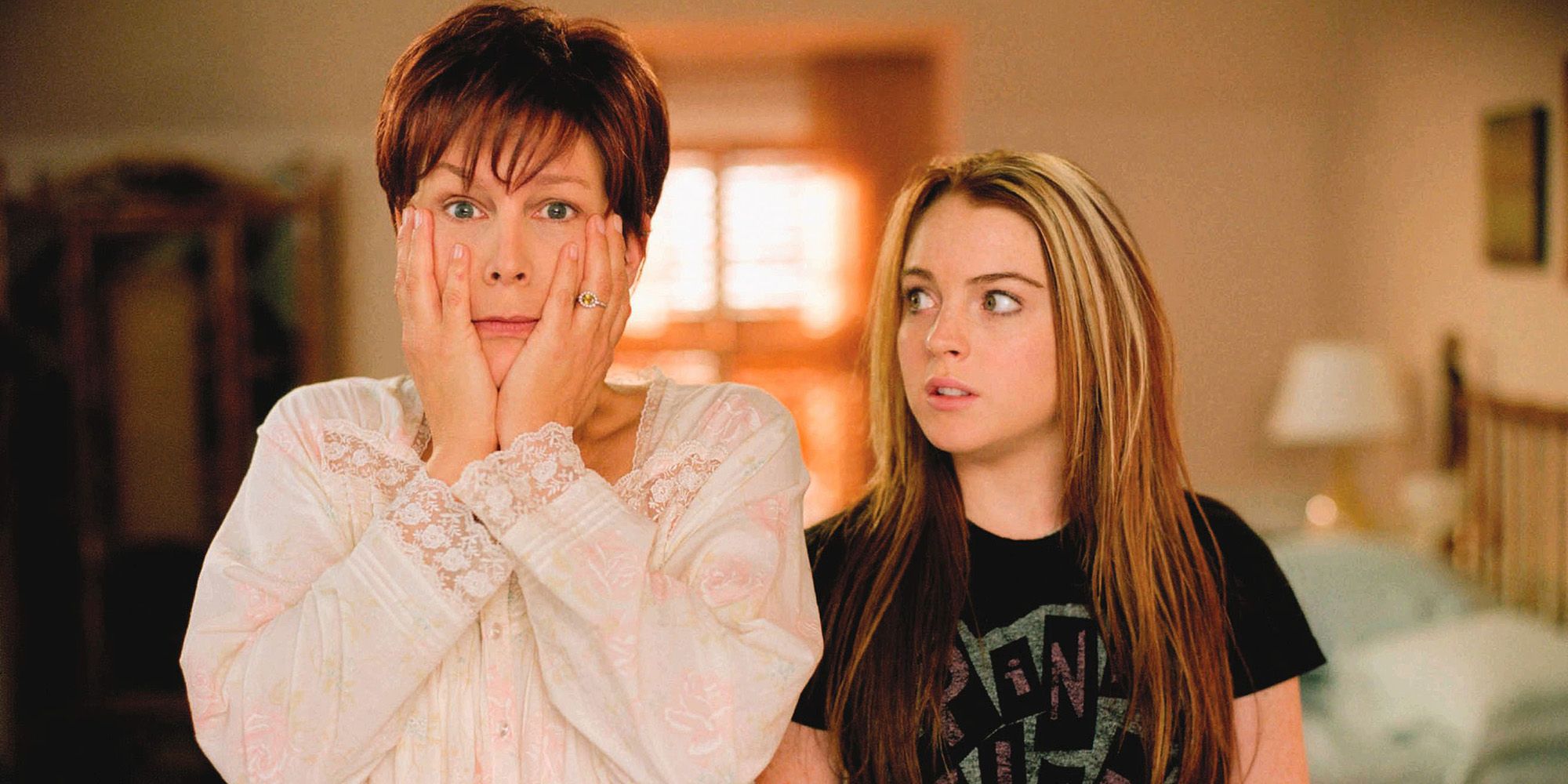 Jamie Lee Curtis holding her face while Lindsay Lohan looks at her in Freaky Friday. 