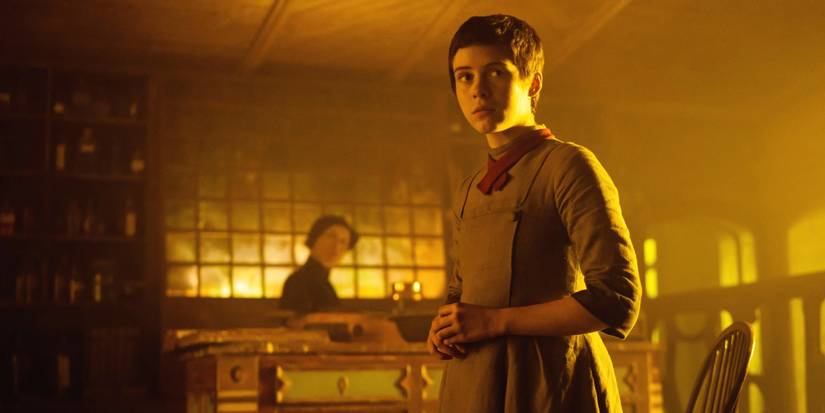 Gretel (Sophia Lillis) berdiri di rumah penyihir yang memikat, berjemur dalam cahaya keemasan yang hangat di 'Gretel & Hansel' (2020)