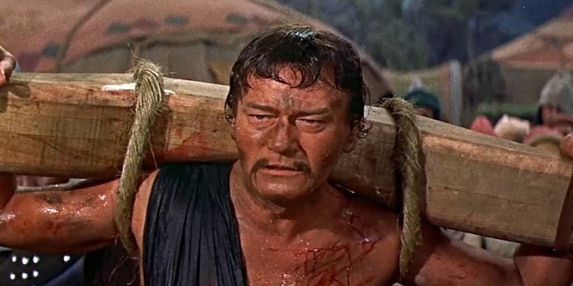John Wayne sebagai Ghenghis Khan, membawa tiang kayu dan berdarah di The Conqueror