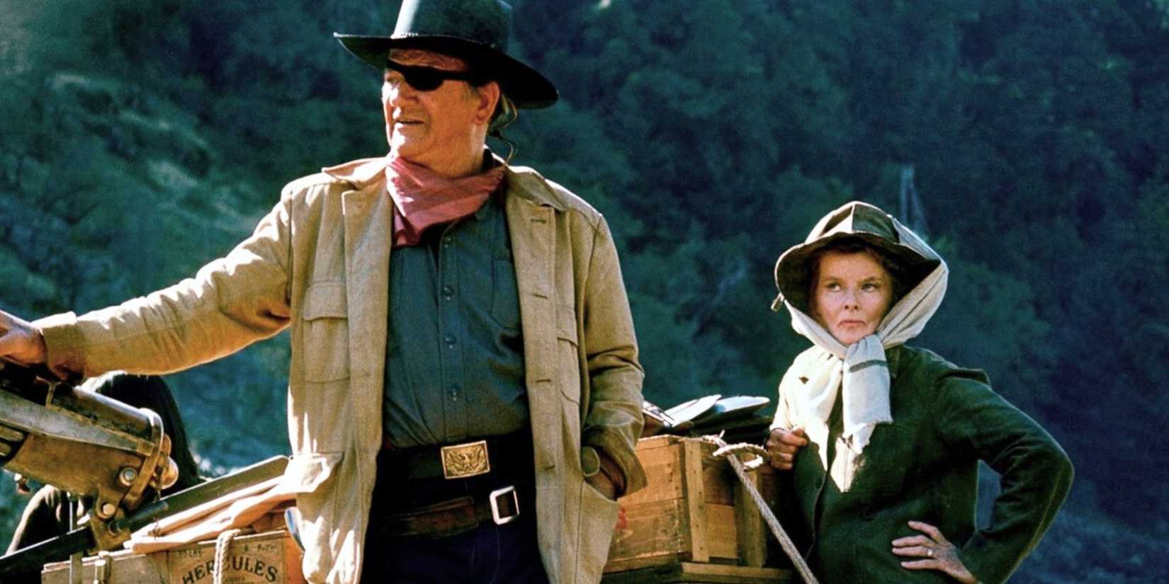 John Wayne as Rooster Cogburn standing with Katharine Hepburn as Eula Goodnight in Rooster Cogburn (1975)