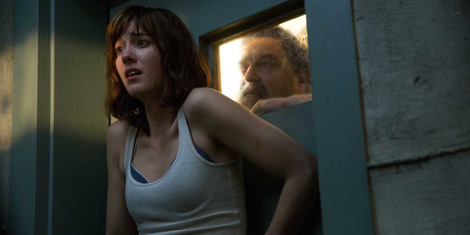 A scared Michelle pressing her body against a door to stop Dan from entering in 10 Cloverfield Lane
