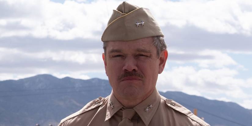 Matt Damon as Leslie Groves standing in the desert in Oppenheimer.