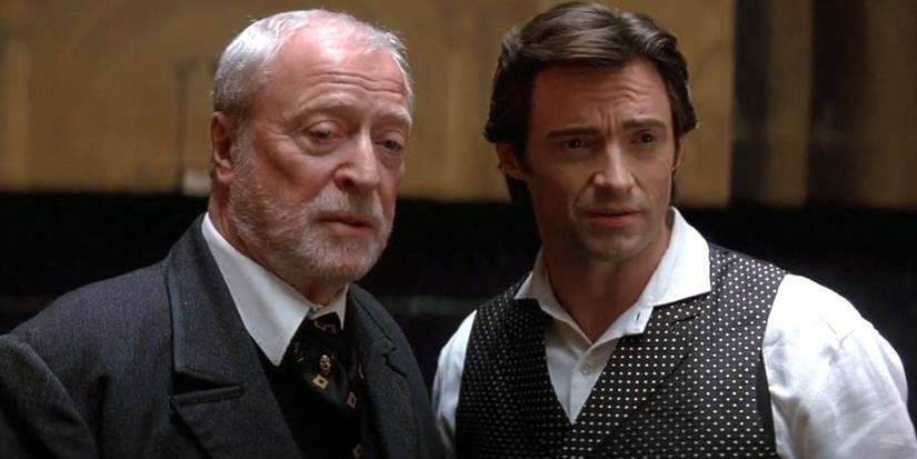 Michael Caine as John Cutter and Hugh Jackman as Robert Angier look in the same direction in The Prestige.