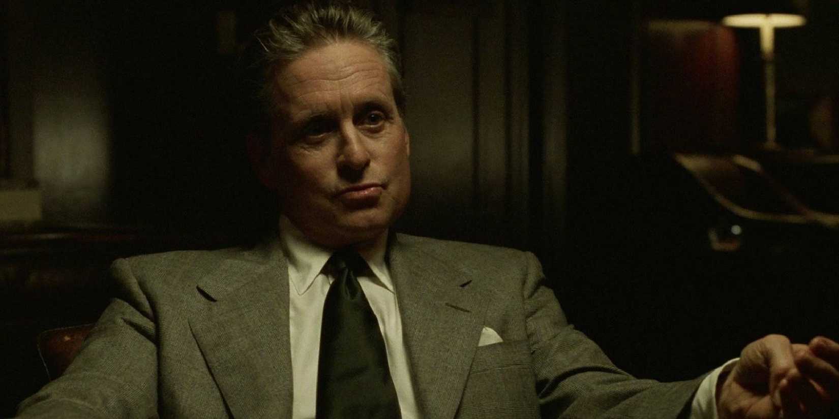 Michael Douglas sits in a chair and looks contemplative in The Game.