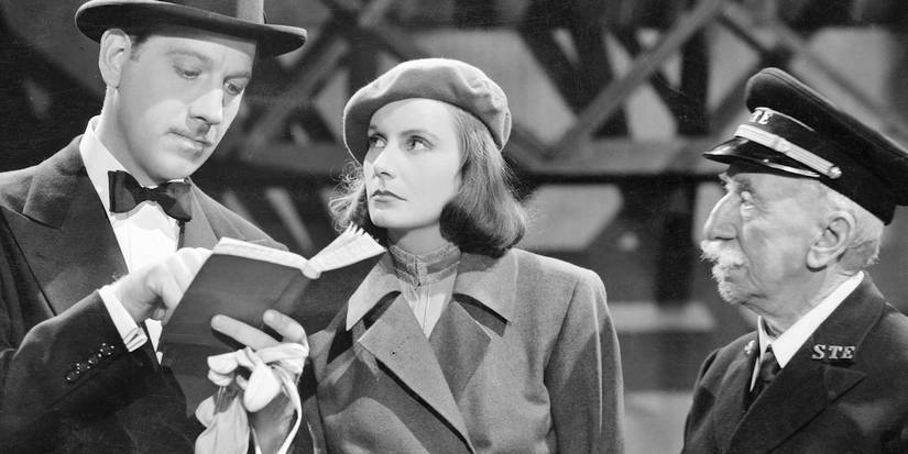 Greta Garbo looking at a man reading a little notebook