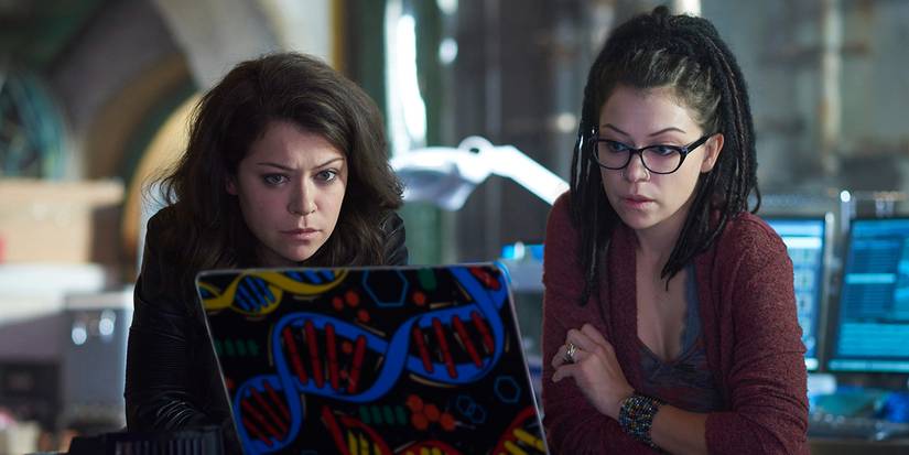 Two clones, one with straight hair another with dreads, looking at a laptop in Orphan Black.