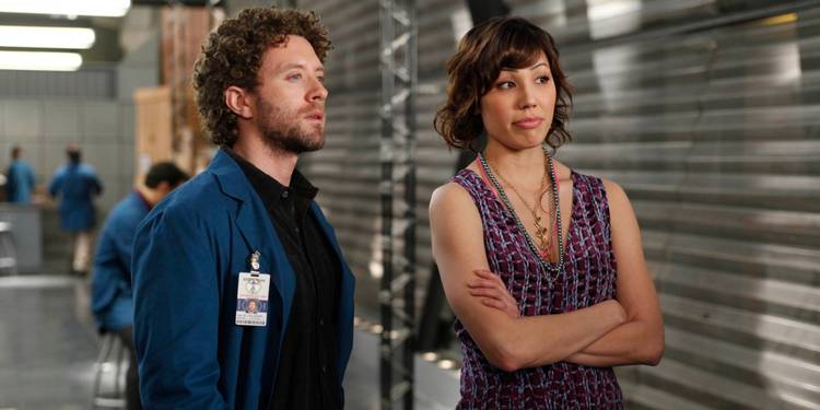 Hodgins (T.J. Thyne) and Angela (Michaela Conlin) stand together and look at something offscreen while Angela crosses her arms in Bones