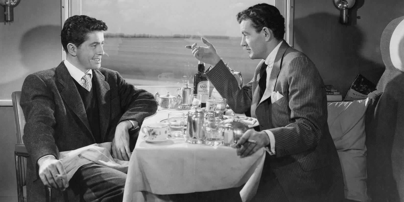 Guy and Bruno chatting at a dinner table on a train in ‘Strangers on a Train’.