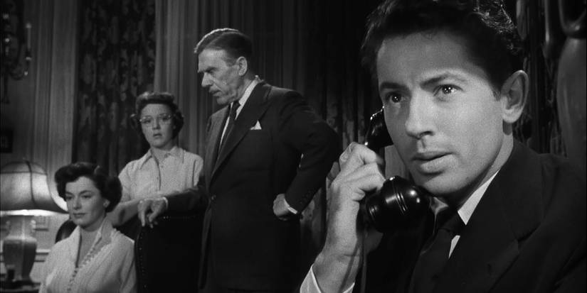 In ‘Strangers on a Train,’ Guy (Farley Granger) looks concerned on the phone while Anne, Barbara, and Senator Morton wait in the background.
