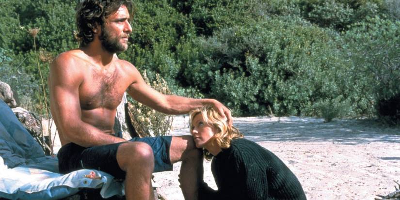 Amber (Madonna) sits on the beach, resting her head on Giuseppe's (Adriano Giannini) knee in 'Swept Away' (2002).